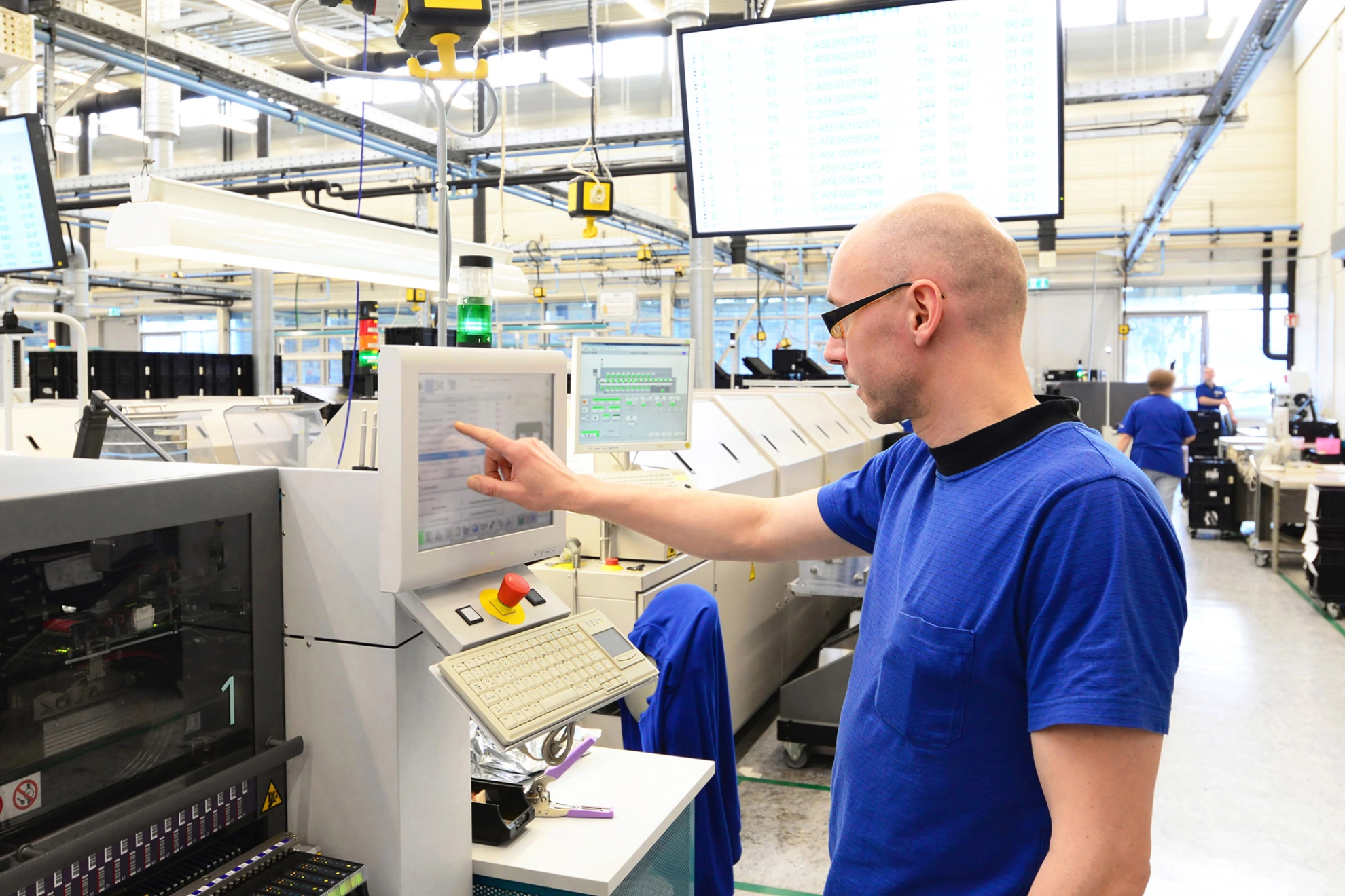 Ein Beschäftigter bedient den Monitor einer Maschine in einer High-Tech-Fabrik.