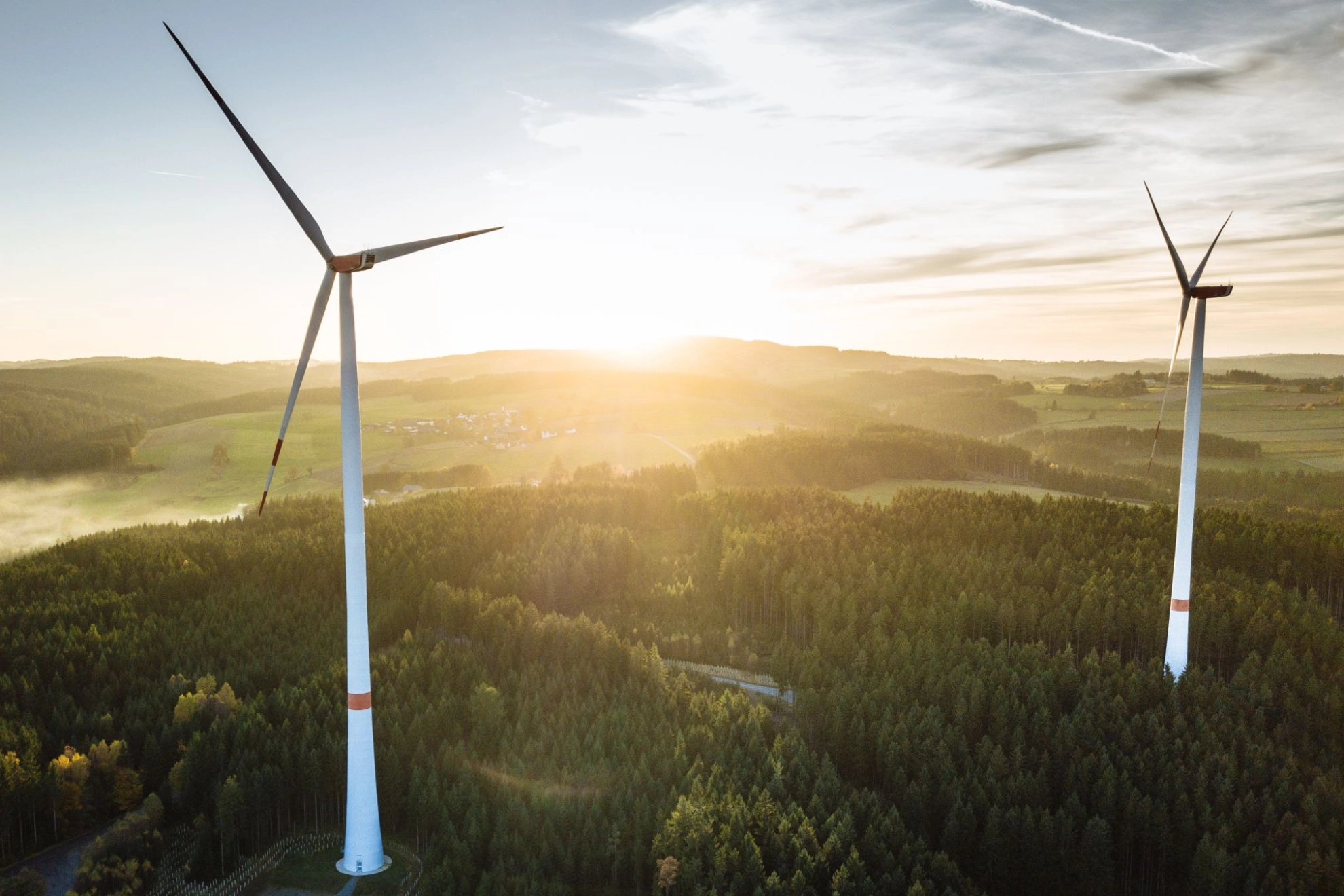 zwei Windkraftanlagen während eines Sonnenuntergangs